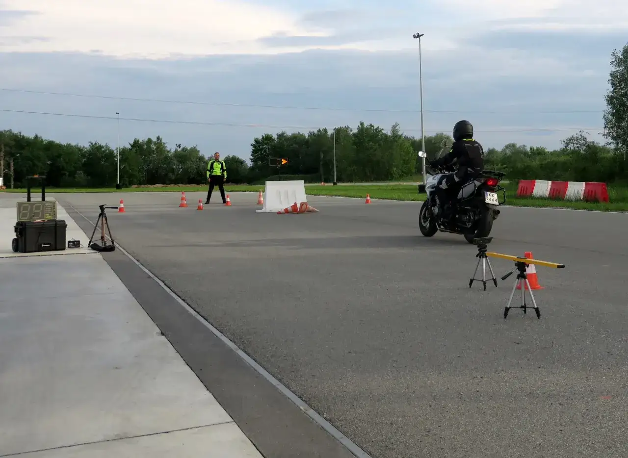 Motocyklista na placu manewrowym, egzaminator i sprzęt do pomiaru prędkości. Zastanawiasz się, ile trwa kurs na prawo jazdy kat A?