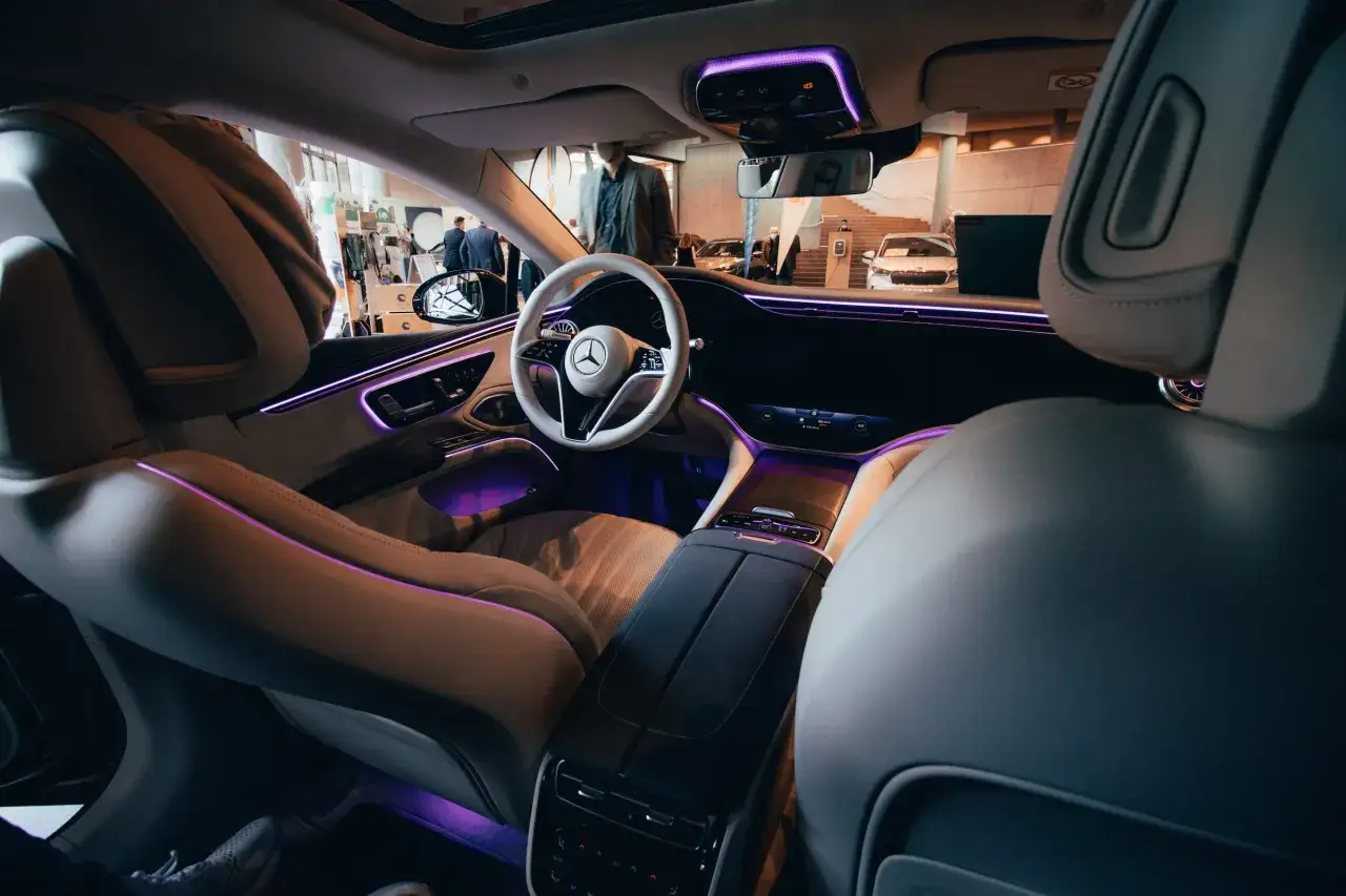 Wnętrze luksusowego hej mercedes z fioletowym ambientowym oświetleniem, skórzanymi fotelami i nowoczesną deską rozdzielczą.