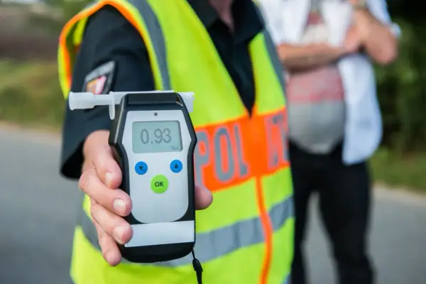 Policjant w kamizelce odblaskowej pokazuje alkomat z wynikiem 0.93 promila. Rutynowa kontrola trzeźwości na drodze.
